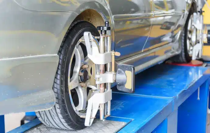 Wheel Alignment In Castle Rock CO At Titan Auto Tech European & Import Auto Repair. A close-up of a cars front wheel on an alignment machine in an auto repair shop, showing the alignment clamp and sensor attached to the tire.