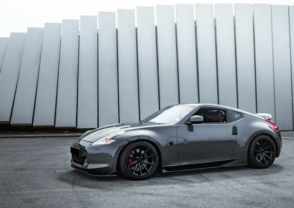 Nissan Repair In Castle Rock CO At Titan Auto Tech European & Import Auto Repair. A sleek, gray sports car is parked on black pavement in front of a modern building with large, angled metal panels.