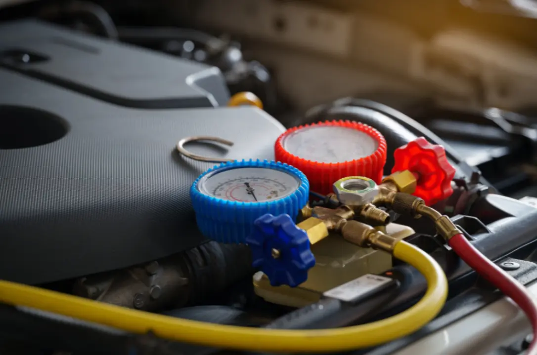 Auto a/c repair and cooling system service, auto repair in Castle Rock, CO at Titan Auto Tech European & Import Auto Repair. Image of red and blue manifold gauges connected inside a vehicle engine bay to support accurate air conditioning system testing and performance.