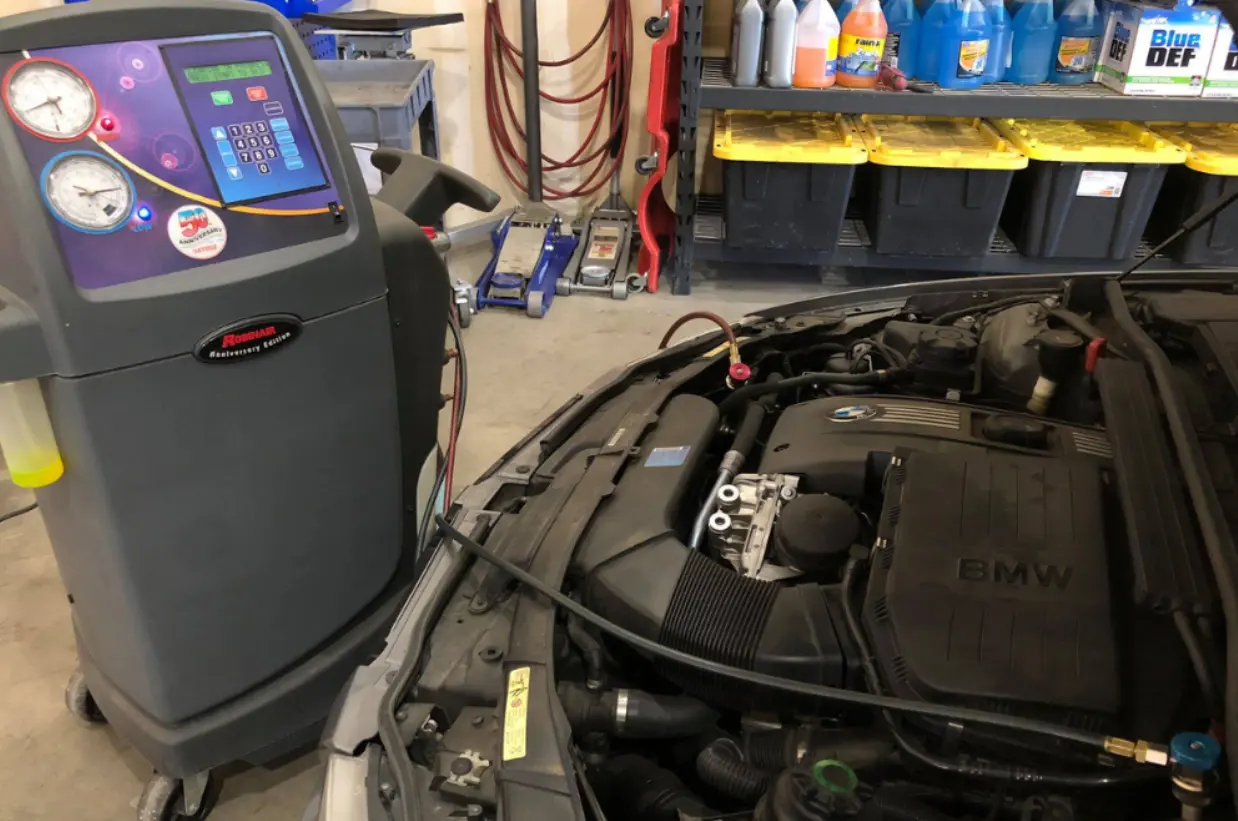Auto a/c service, auto repair in Castle Rock, CO at Titan Auto Tech European & Import Auto Repair. Image of a BMW engine bay connected to a refrigerant service machine for reliable climate control performance.